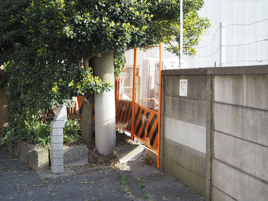 通りのオレンジ色のフェンスと木々、光が差し込む風景 / Orange fence and trees on a street with sunlight streaming through