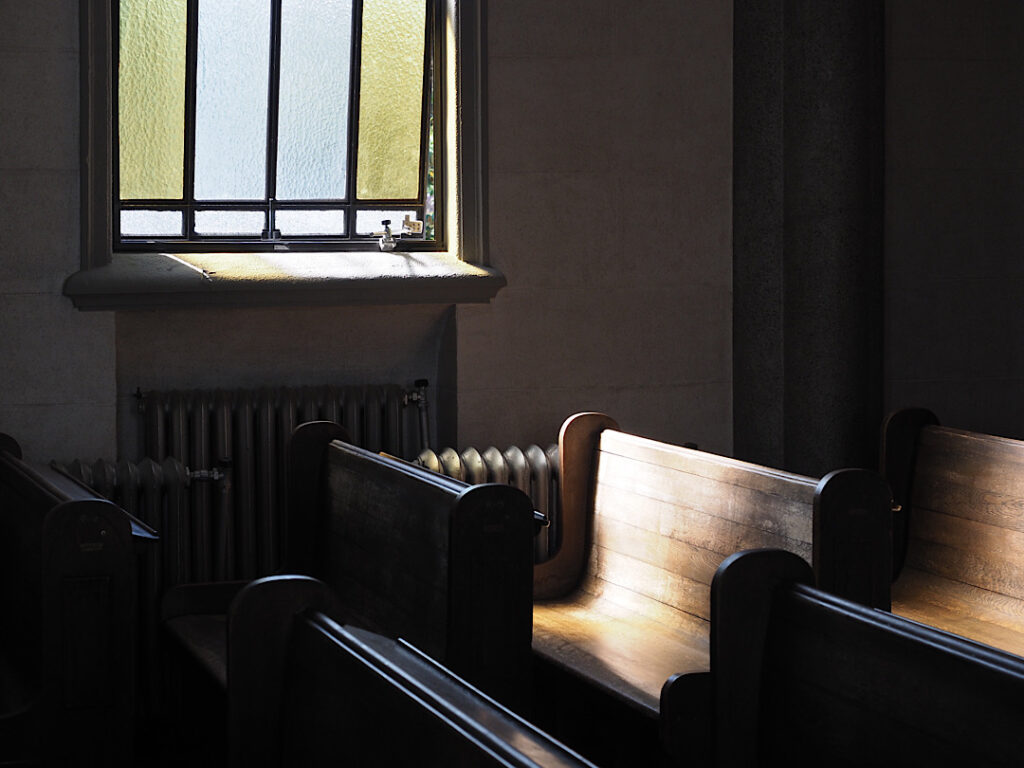 椅子と窓から柔らかな光が差し込む静かな教会のインテリア/ Quiet church interior with chairs and soft sunlight through windows